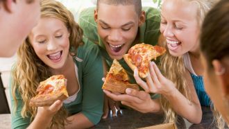Three teens eating pizza