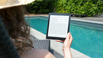 Woman reads a tablet beside a swimming pool
