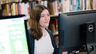 a woman sits looking at a library computer screen