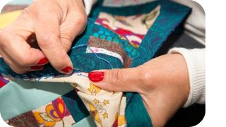 Hands quilting with needle and thread.