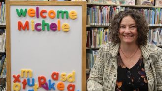 Michele Schoen, Wright Library Youth Services Coordinator, poses in front of children's book section.