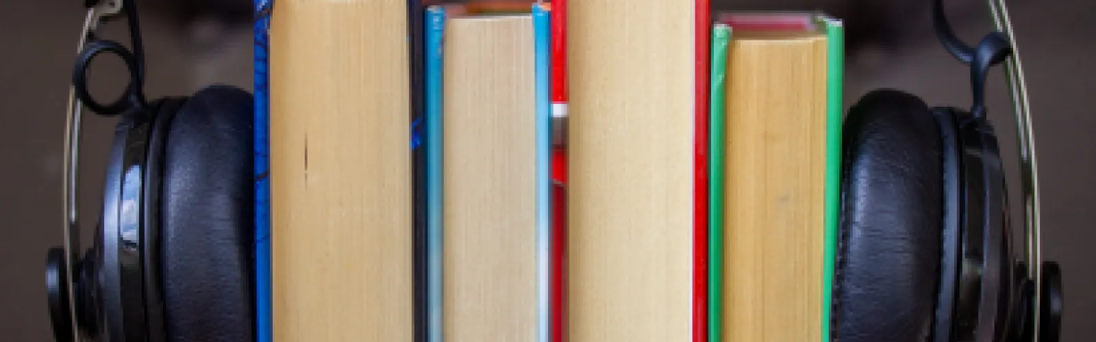 Headphones around four stacked books.